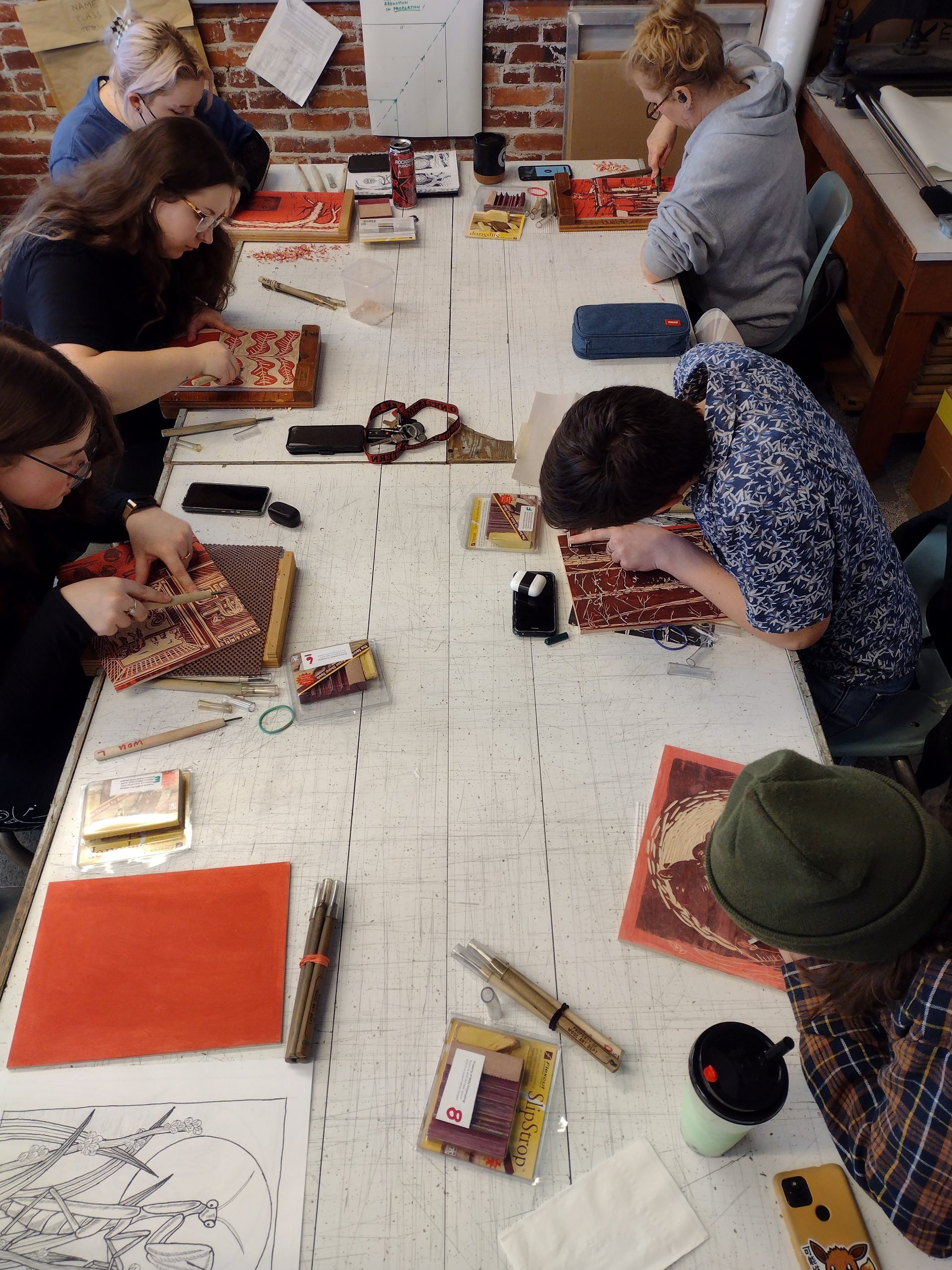 WOU Art Students gathered around a table, carving linoleum blocks.