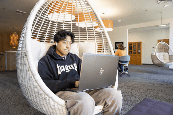 unnamed (1) Student in basket chair with a laptop on their lap