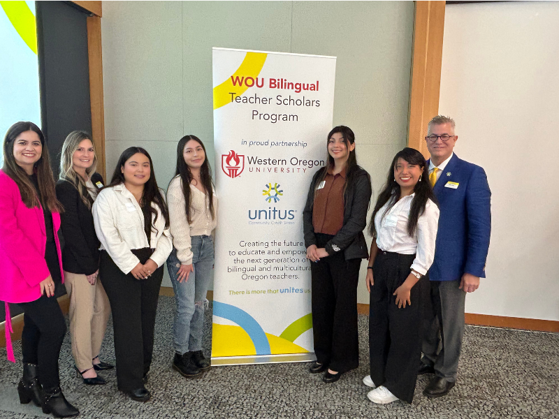 Bilingual scholarship winners standing in from of unitus scholarship banner. 