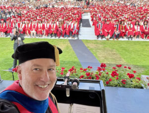 Man taking a selfie with a large crowd behind him