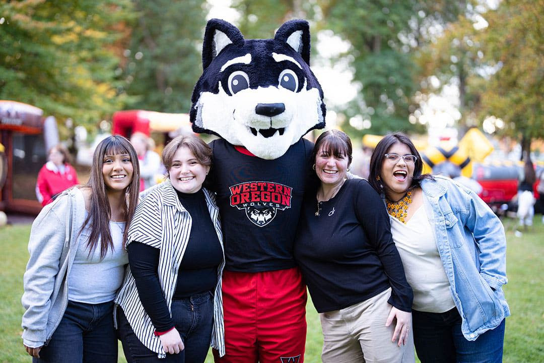Four people standing next to a wolf mascot