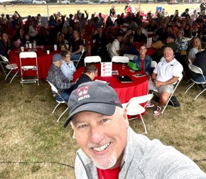 Man taking a selfie with a large crowd behind him