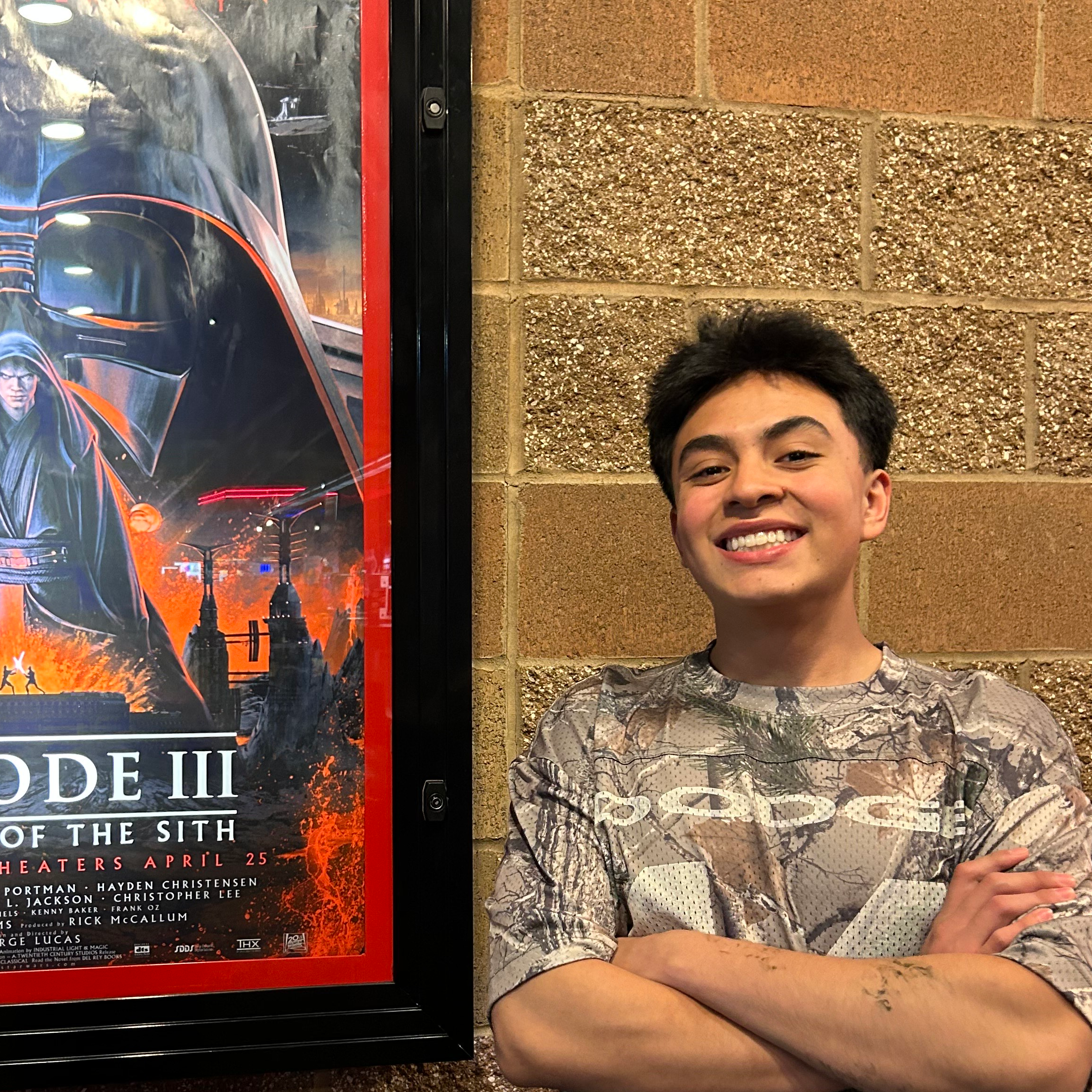 A man smiling in front of a movie poster.